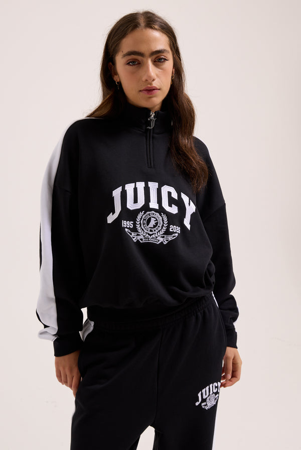 Displays a model wearing the Black 'Juicy' branded college crest track top 
