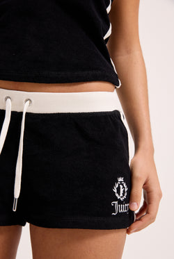 Displays a model wearing the Black Appliqué 'Juicy' branded  Terry booty shorts featuring the juicy branding 