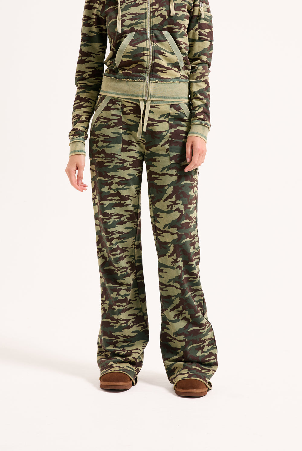 Displays a model wearing the Camo Print 'Juicy' branded washed cotton low rise track bottoms