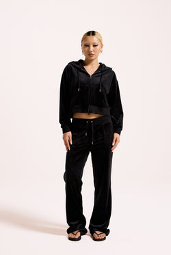 Displays a model wearing the Black 'Juicy' branded crop oversized classic velour hoodie 