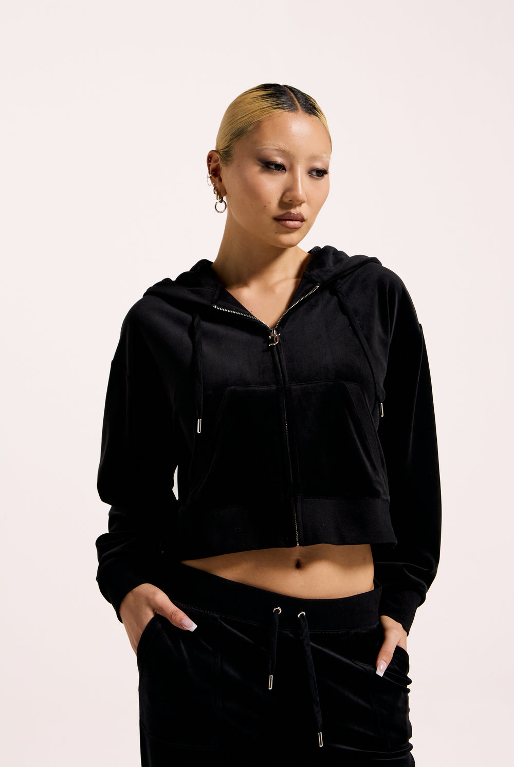 Displays a model wearing the Black 'Juicy' branded crop oversized classic velour hoodie 