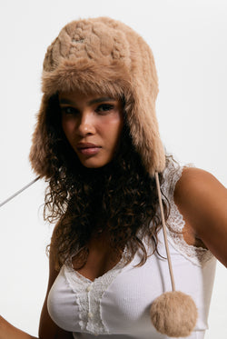 Displays a model wearing the Warm Taupe 'Juicy' branded Cable Knit Trapper With Fur Lining