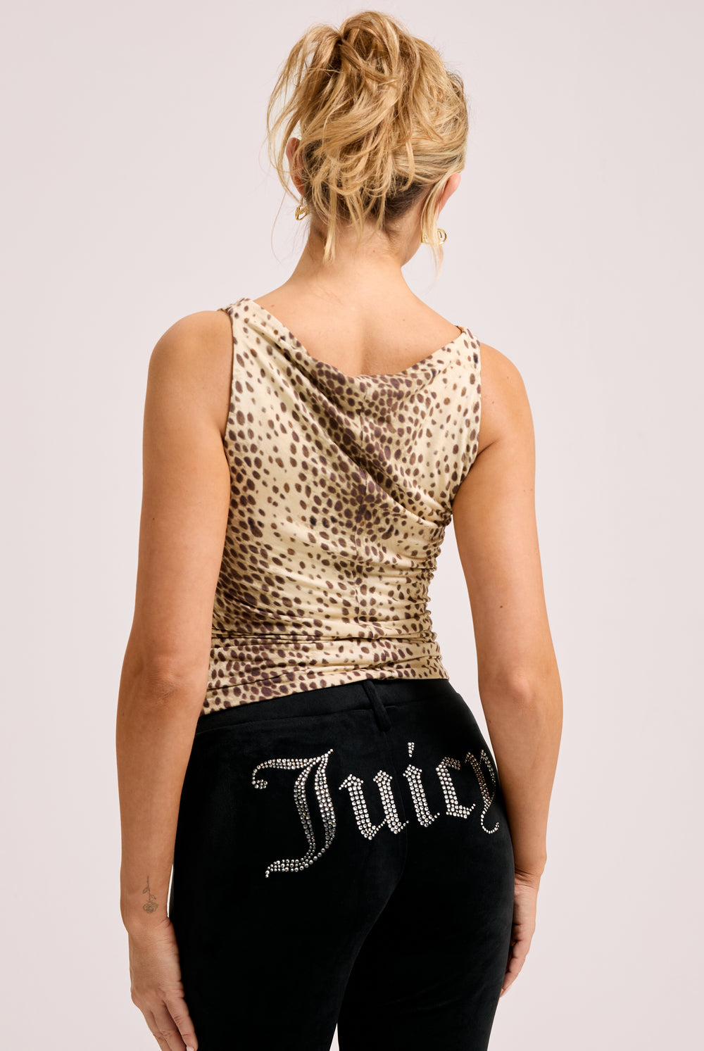 Displays a model wearing the natural cheetah print 'Juicy' off the shoulder top 