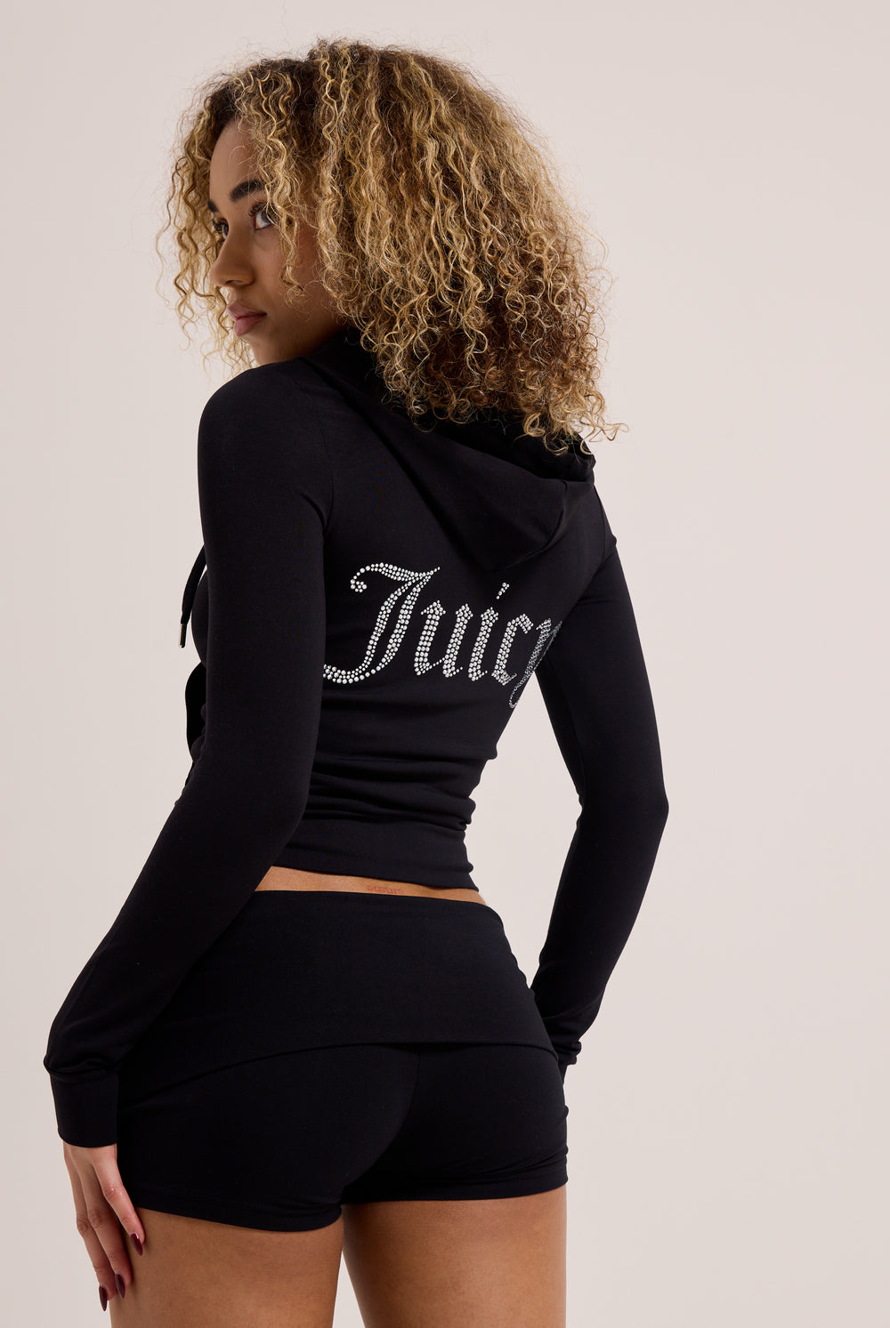 Displays a model wearing the Black 'Juicy' Branded Luxury Jersey Roll down Diamanté shorts with the matching juicy top