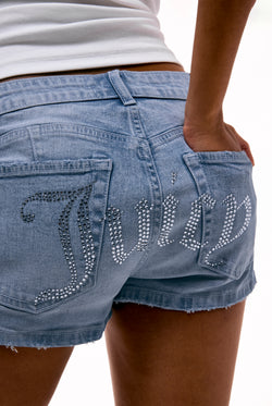 Displays a model wearing the Light Wash 'Juicy' low rise denim booty short featuring the juicy branding 
