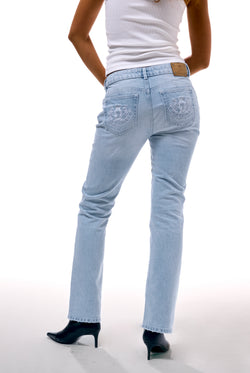 Displays a model wearing the Light Wash 'Juicy' branded Dog crest bootcut jeans