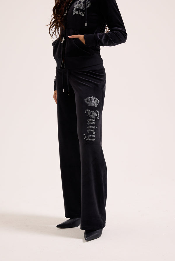 Displays a model wearing the black 'juicy' branded diamanté crown OG Straight low rise velour bottoms 