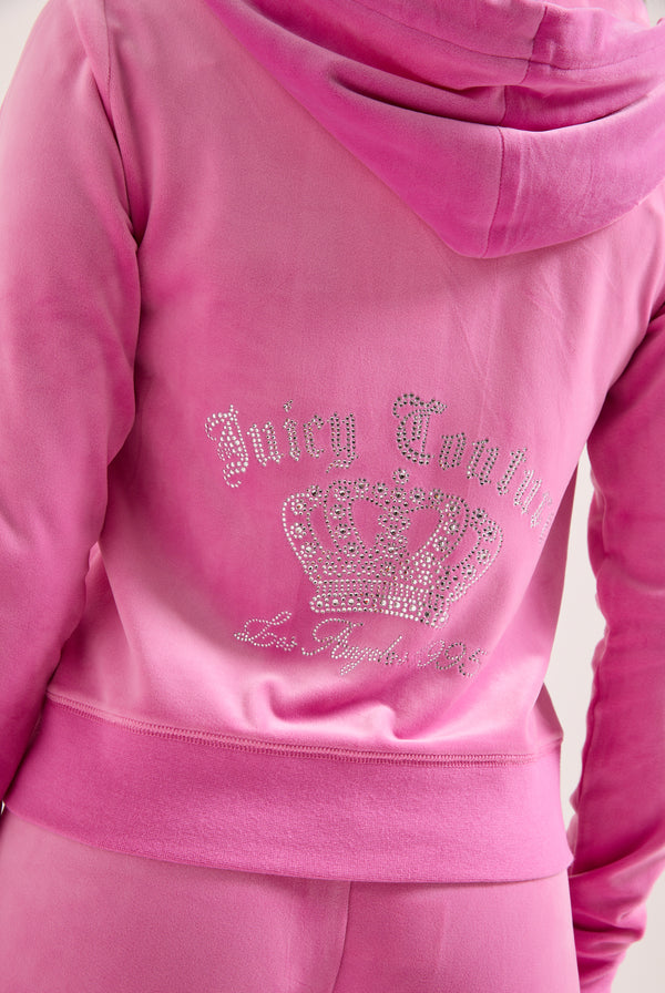 Displays a model wearing the super pink 'juicy' branded gothic crown classic velour hoodie featuring the juicy couture branding 