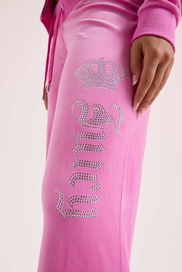 Displays a model wearing the super pink 'Juicy' branded diamanté crown OG straight low rise velour bottoms 