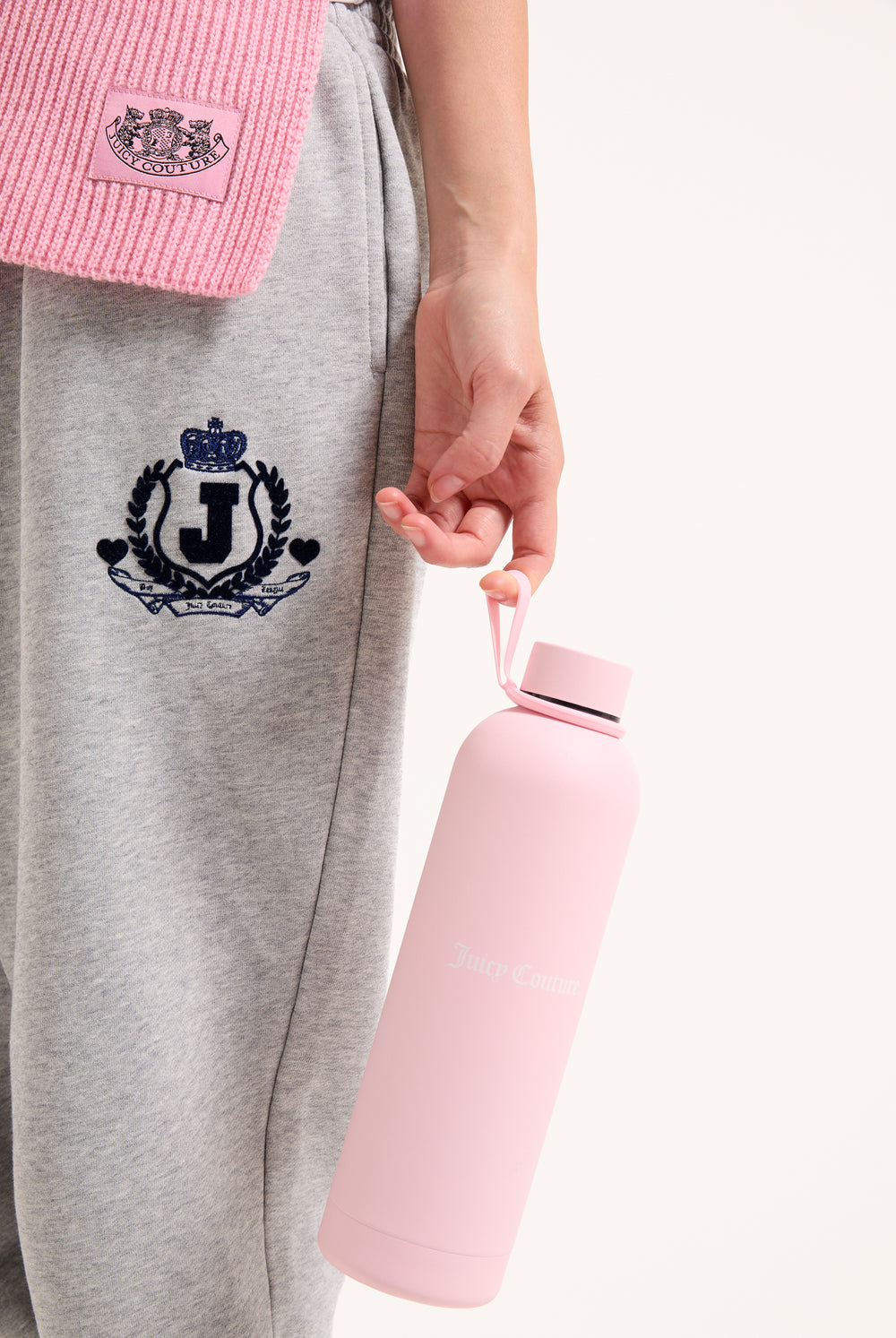 Displays a model holding the Pink 'Juicy' branded heritage crest water bottle 
