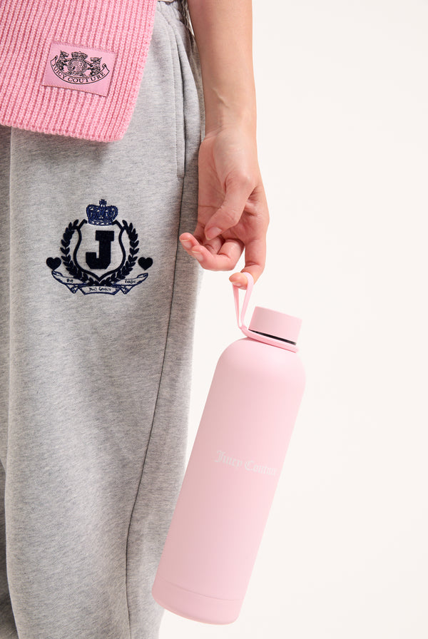 Displays a model holding the Pink 'Juicy' branded heritage crest water bottle 