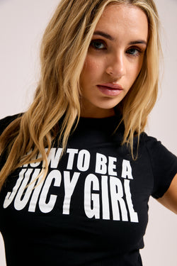Displays a model wearing the Black 'Juicy' branded HOW TO BE A JUICY GIRL T-SHIRT