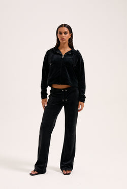 Displays a model wearing the Black 'Juicy' branded outline diamanté oversized cropped hoodie 