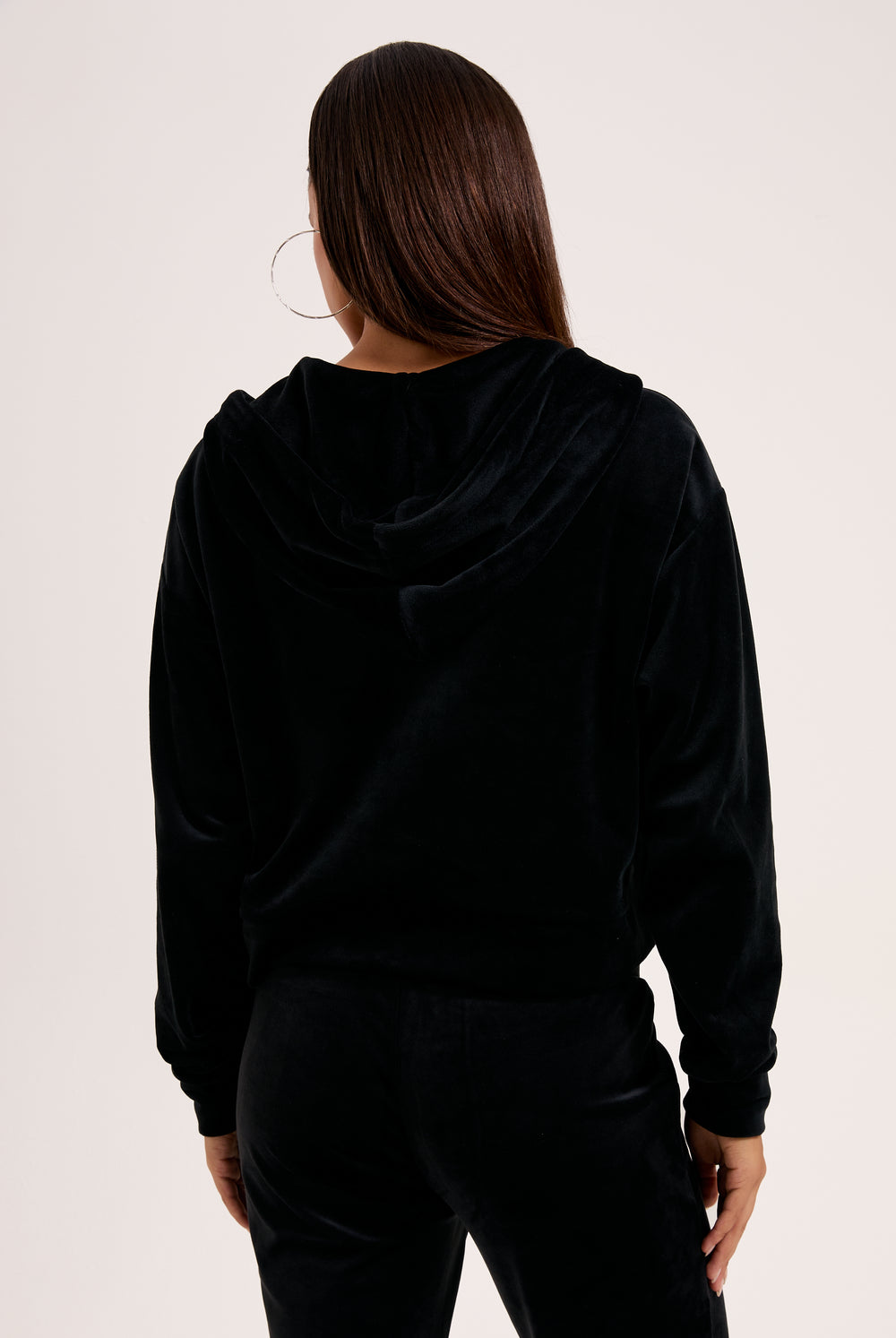 Displays a model wearing the Black 'Juicy' branded outline diamanté oversized cropped hoodie 