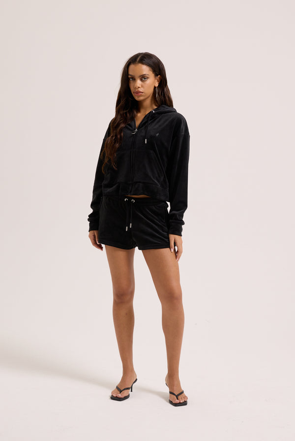 Displays a model wearing the Black 'Juicy' branded velour outline diamanté track shorts 