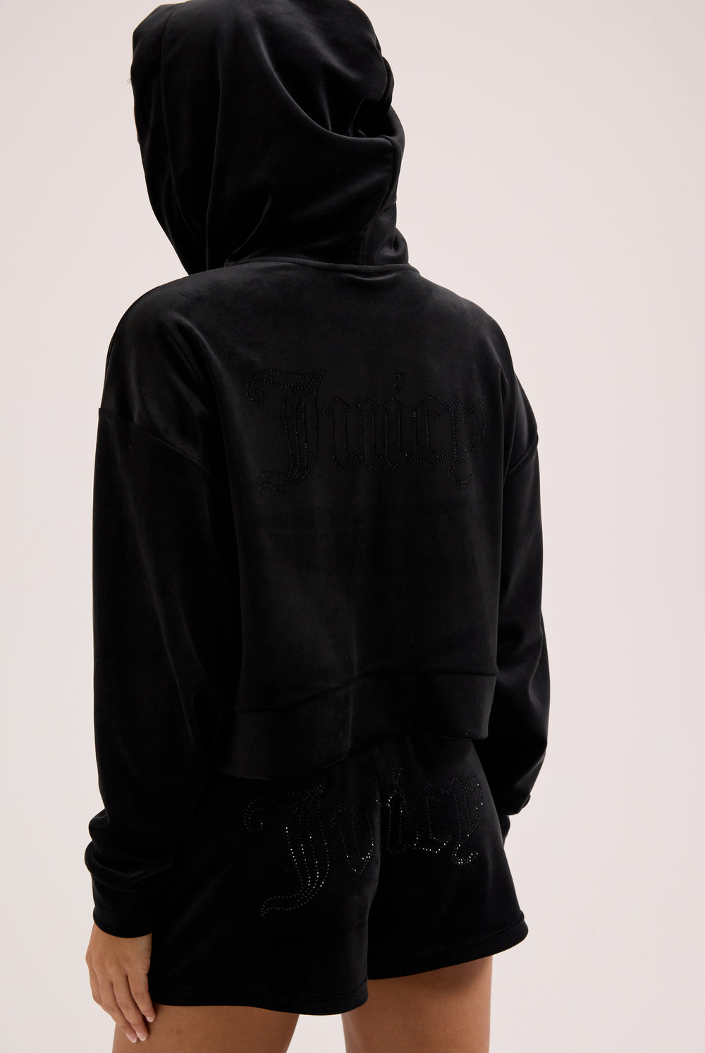 Displays a model wearing the Black outline 'Juicy' branded diamanté oversized cropped hoodie 