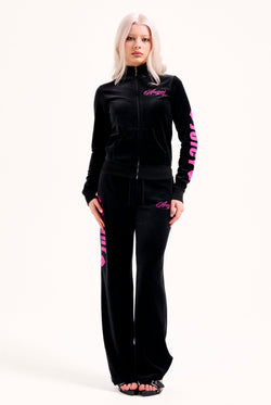 Displays a model wearing the Black 'Juicy' branded angel cotton velour track top