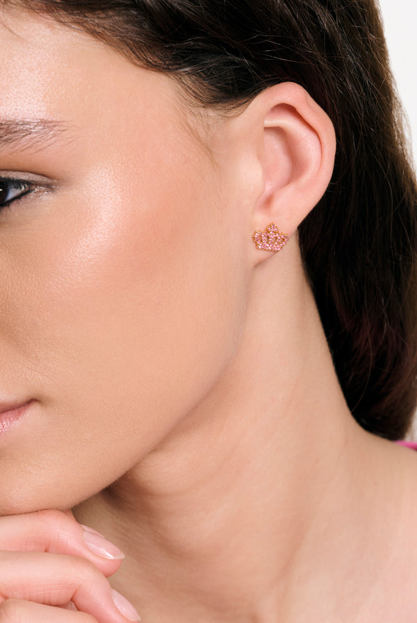Displays a model wearing the Gold Tone 'Juicy' branded crystal motif crown stud earrings 