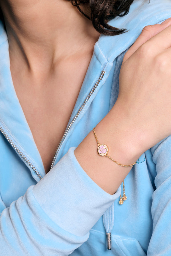 Displays a model wearing the Gold tone 'Juicy' branded love juicy reversible enamel adjustable bracelet 