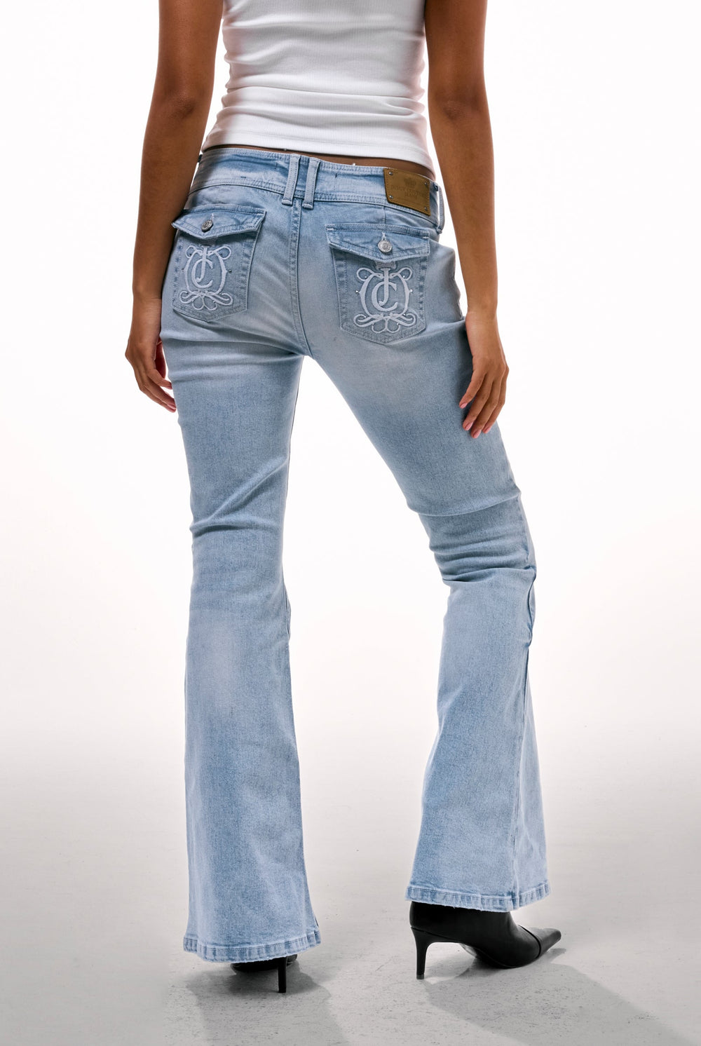 Displays a model wearing the Light wash 'juicy' branded low rise flared embodied jeans 