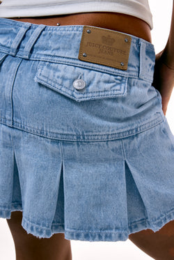 Displays a model wearing the light wash  'juicy' branded denim pleated mini skirt 