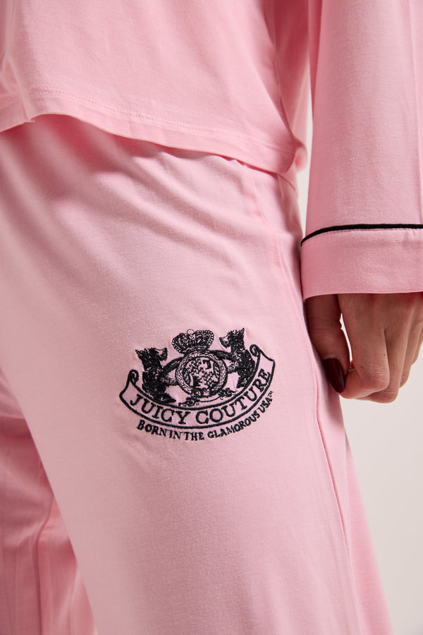 Displays a model wearing the Juicy Pink 'juicy' branded dog crest pyjama set featuring the juicy Couture logo