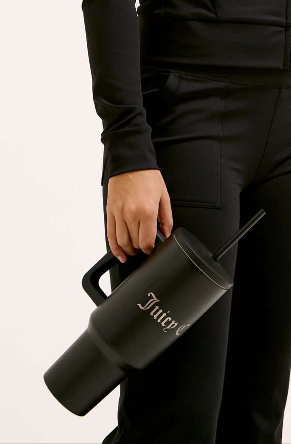 Displays a model holding the Black 'juicy' branded steel tumbler with straw 