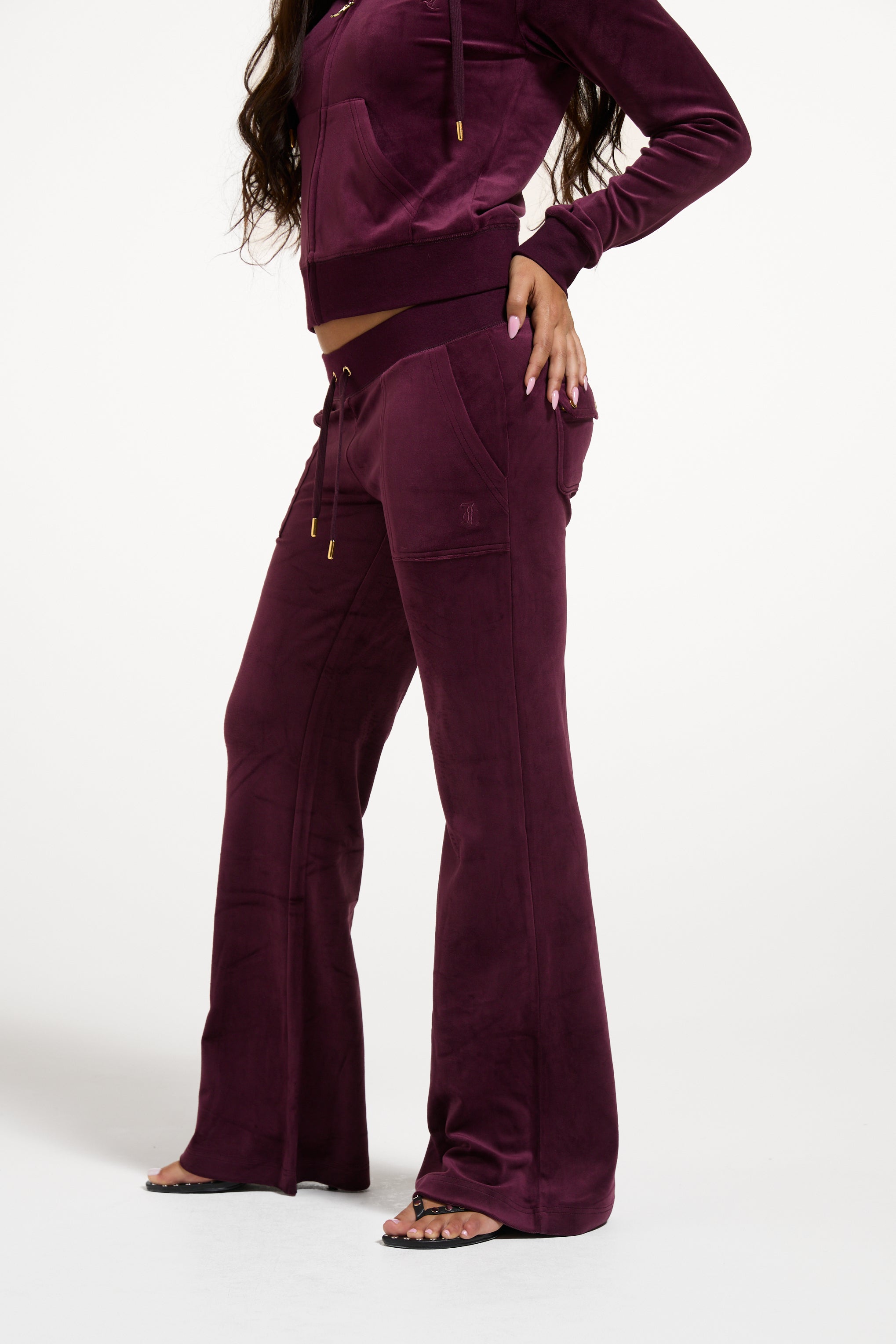 Displays a model wearing the Winetasting & Gold 'Juicy' branded Low Rise Flare Classic Velour Track Pant