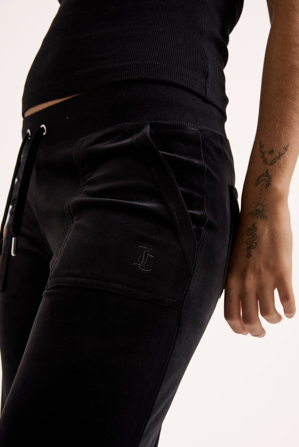 Displays a model wearing the Black Low rise flare pocket 'Juicy' branded classic velour track pant