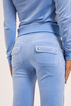 Displays a model wearing the Della Robia 'Juicy' branded low rise flare classic velour track pant 