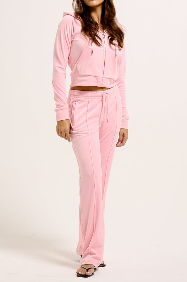 Displays a model wearing the Juicy Pink 'Juicy' branded velour diamanté tracksuit bottoms 