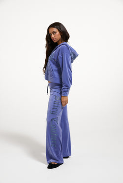 Displays a model wearing the Greyblue 'Juicy' branded Old Gothic Diamante OG Straight Leg Trackpant
