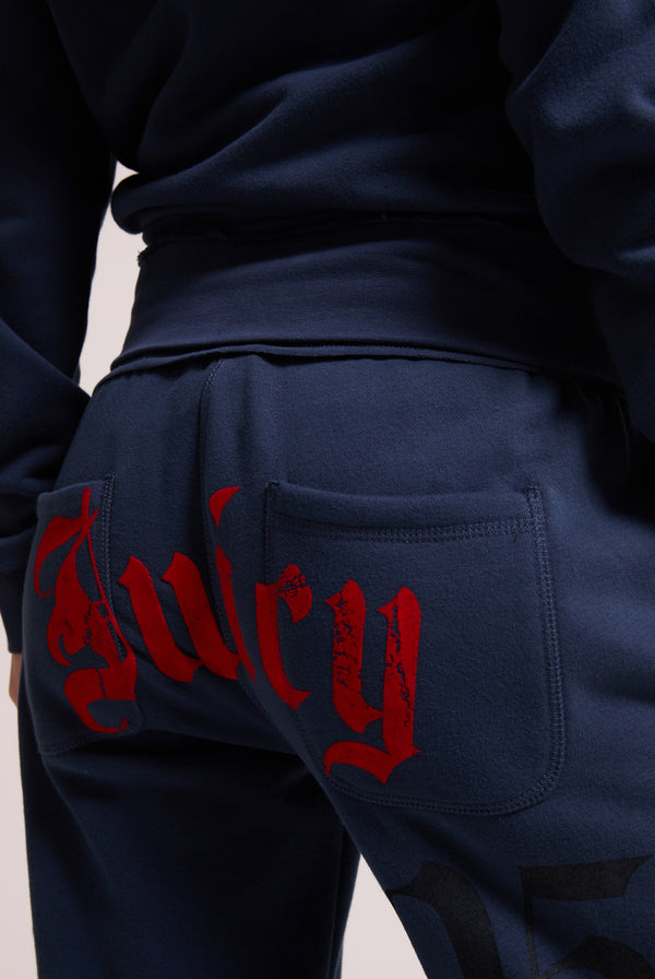 Displays a model wearing the Mood indigo relaxed fit 'juicy' branded flare fleece track pant 