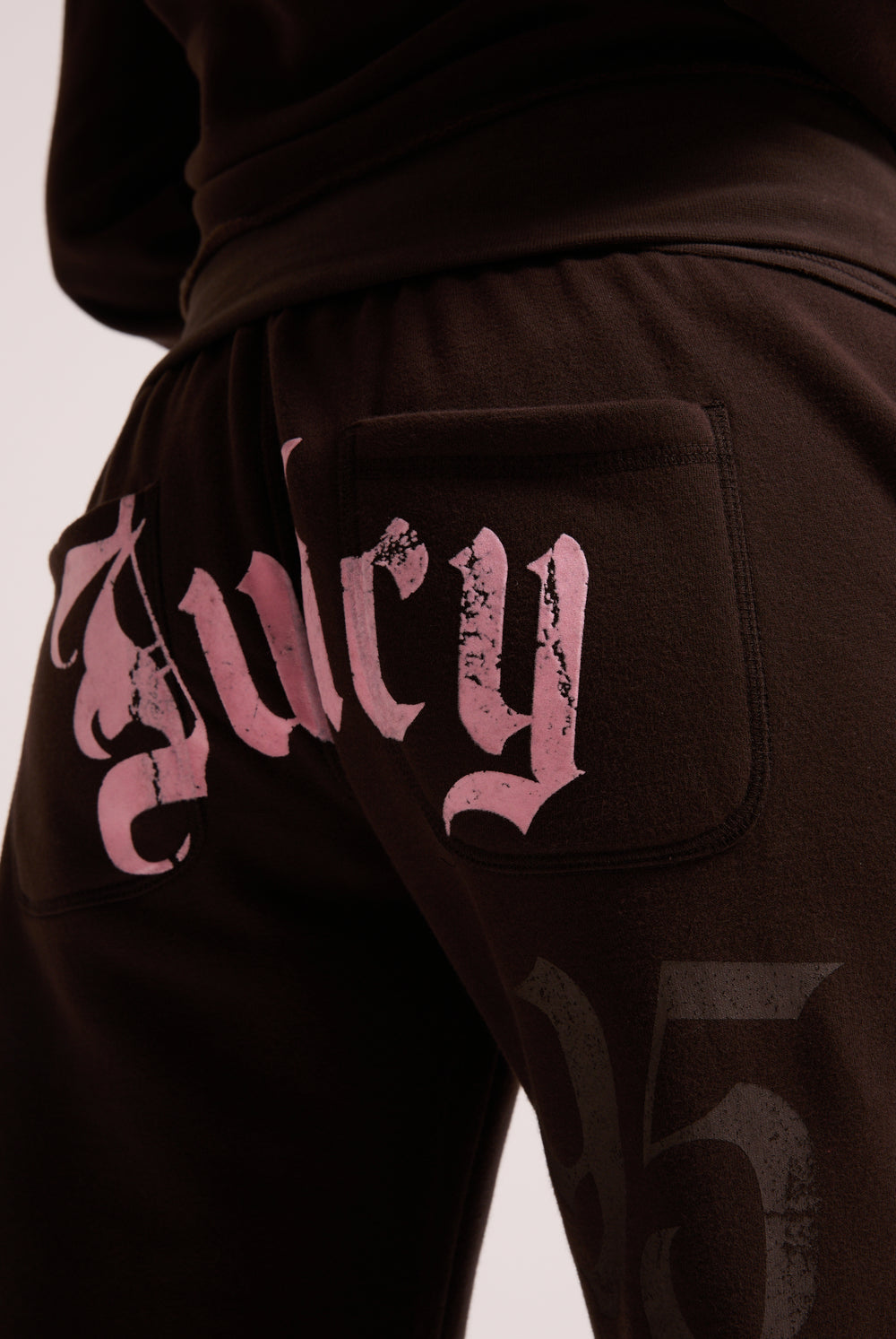 Displays a model wearing the Java 'Juicy' branded relaxed fit flare fleece trackpant featuring the juicy branding 