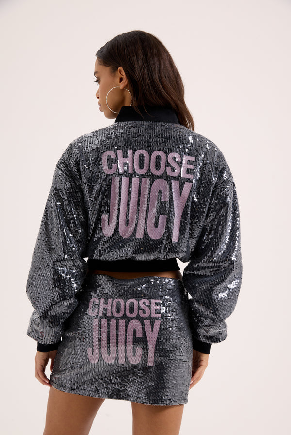 Displays a model wearing the 'juicy' branded choose juicy sequin cropped bomber featuring the juicy branding 