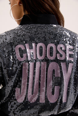 Displays a model wearing the 'juicy' branded choose juicy sequin cropped bomber featuring the juicy branding 