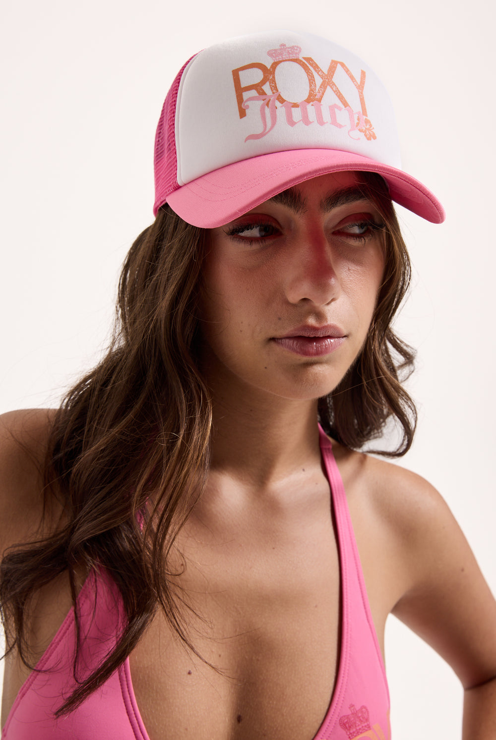 Displays a model wearing the azalea pink Roxy and juicy Couture trucker cap 