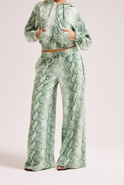 Displays a model wearing the Green snake print 'Juicy' branded diamanté oversized cropped hoodie