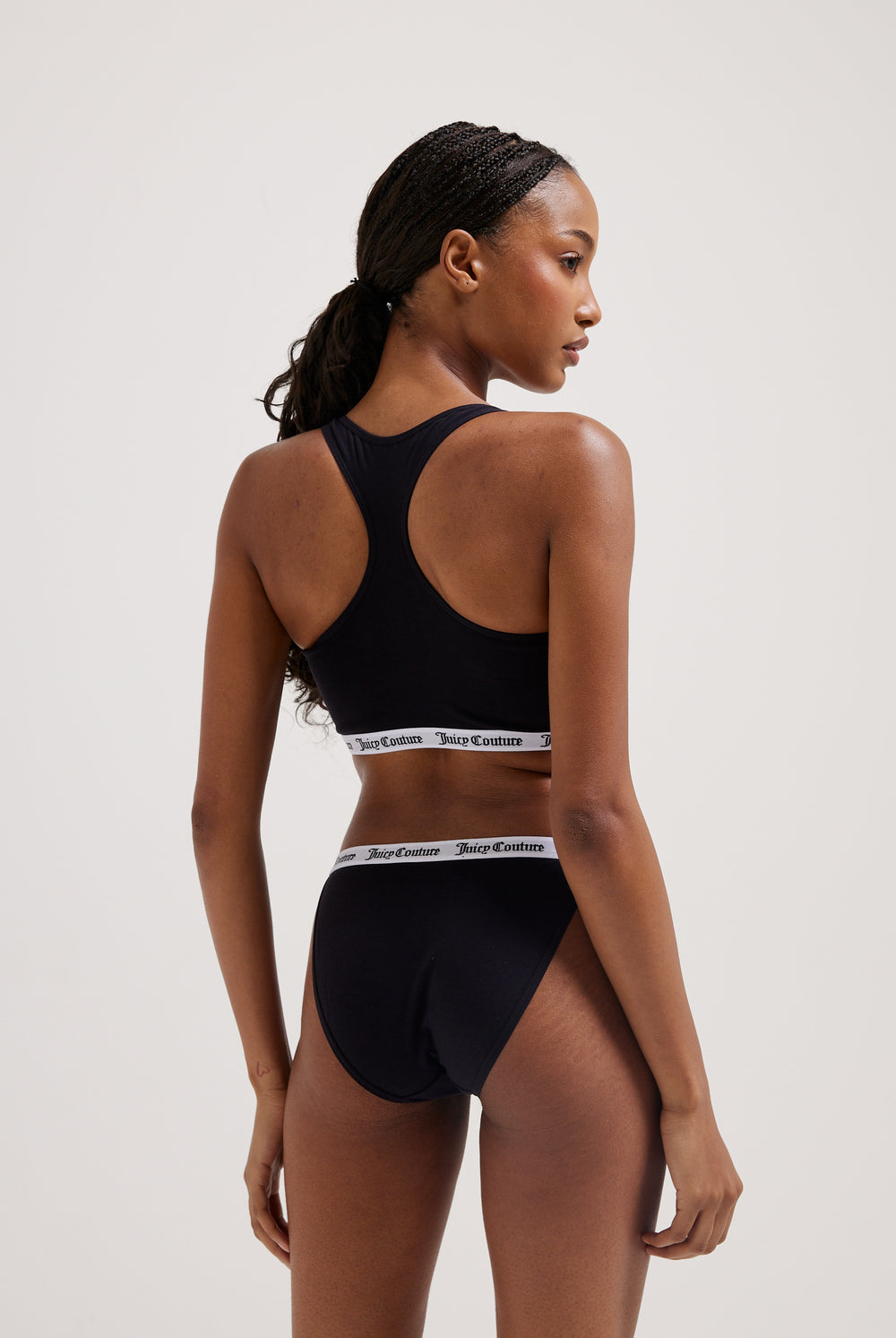 Displays a model wearing the Black 'juicy' branded cotton bralette