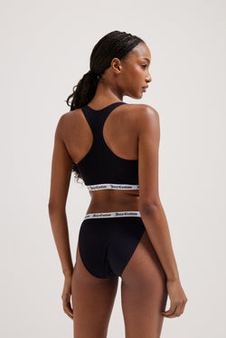 Displays a model wearing the Black 'juicy' branded cotton bralette