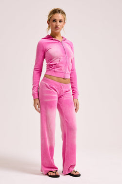 Displays a model wearing the super pink washed 'juicy' branded cotton velour fitted hoodie 