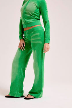 Displays a model wearing the Jolly Green washed 'Juicy' branded OG straight track pant 