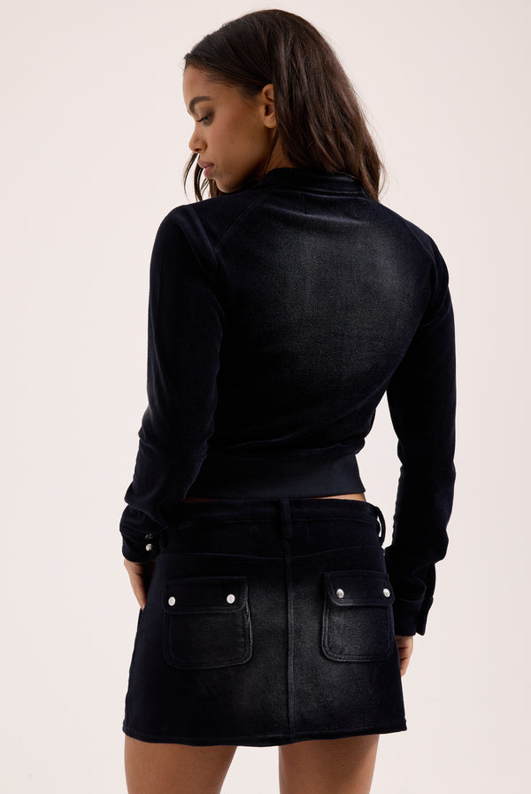 Displays a model wearing the Washed Black 'Juicy' branded Cotton velour mini skirt with the matching Juicy Top