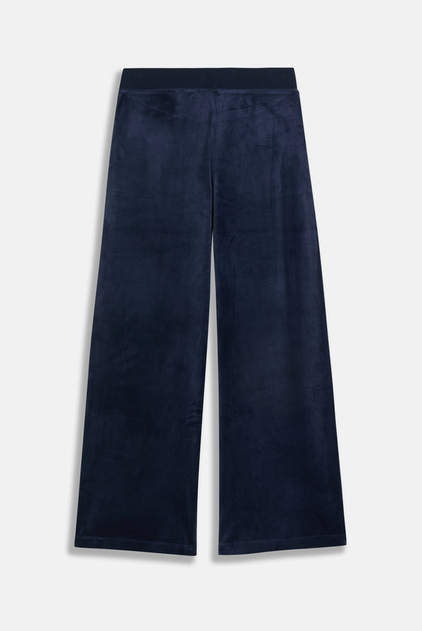 Displays a model wearing the night sky 'juicy' branded Sky Wide leg classic velour track pant 